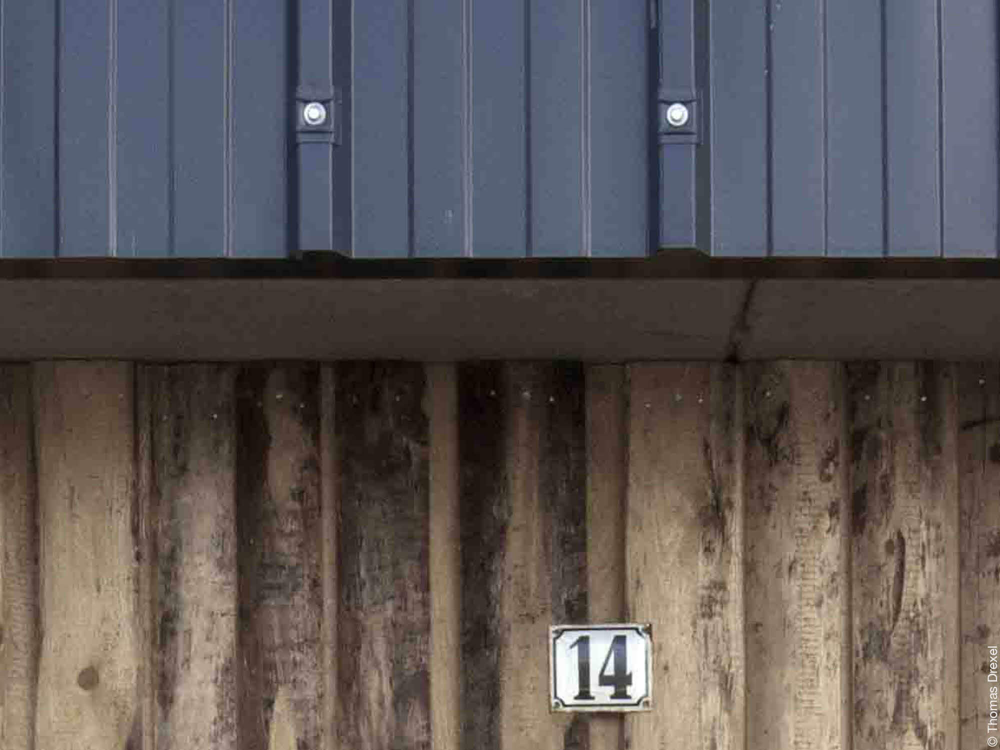 Holzfassade und Blechverkleidung mit Hausnummer