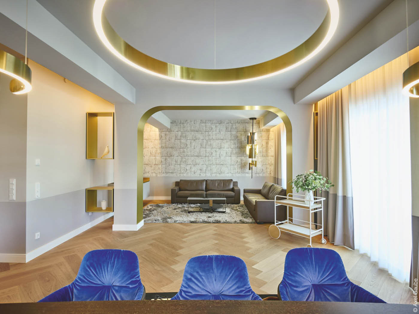 Wohnzimmer mit goldenen Applikationen und blauen Sesseln