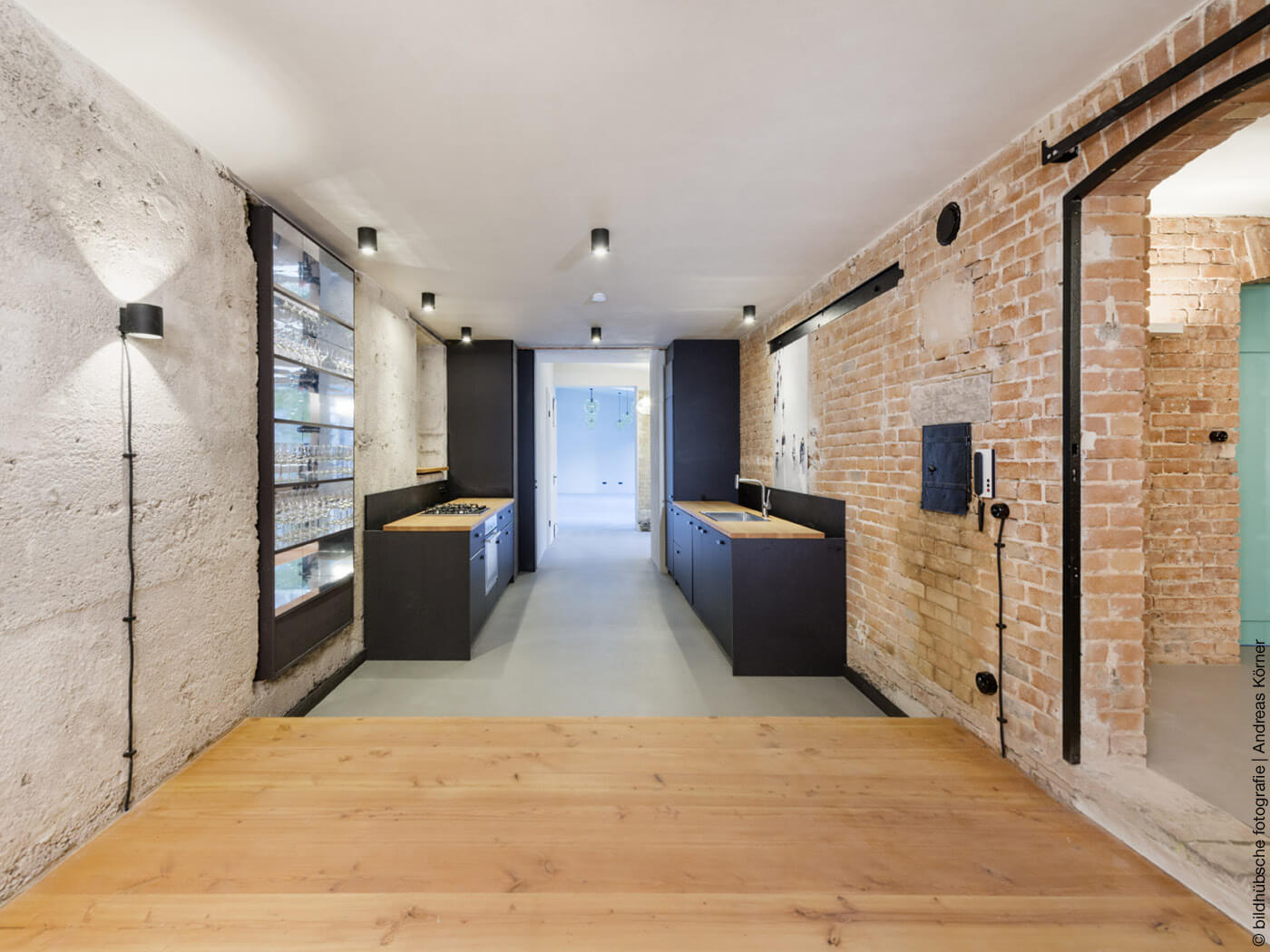 Küche mit schwarzer Küchenzeile und unverputzten Wänden