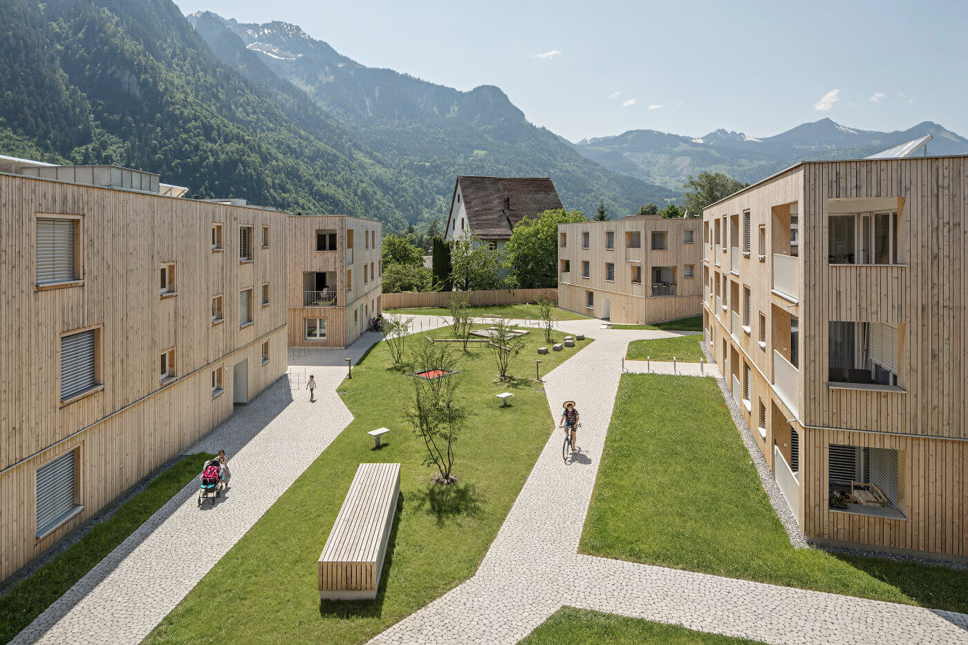 Wohnsiedlung mit Holzfassaden vor Bergen