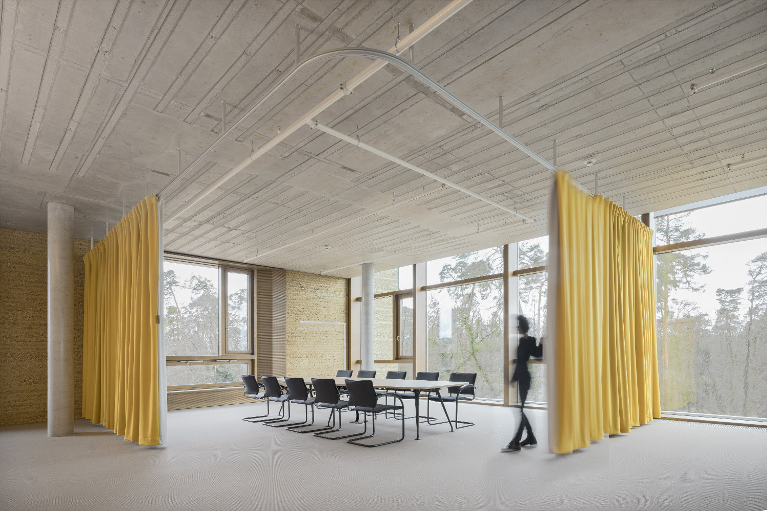 Konferenzraum mit Lehmwand, Fenstern und gelbem Vorhang