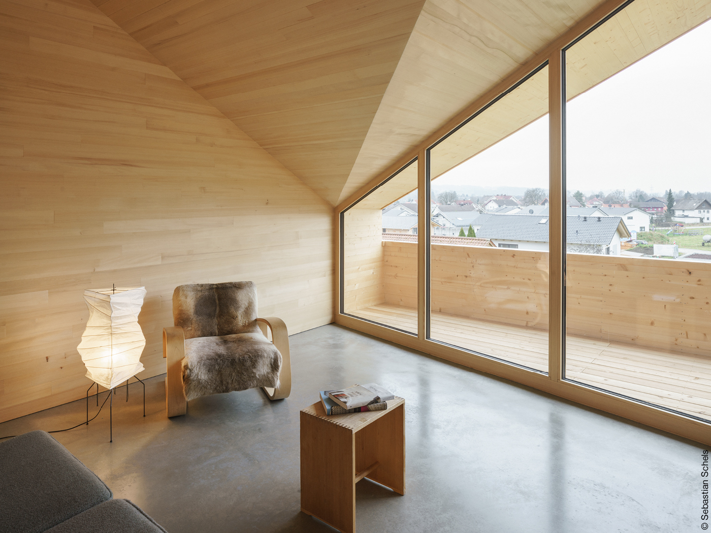 Wohnzimmer unter Dachschräge mit Holzwänden und Glasfassade