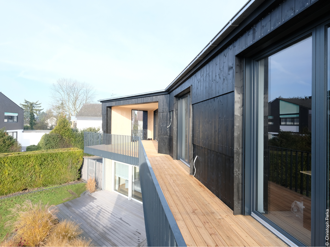 Balkon mit Holzboden und schwarze Holzfassade