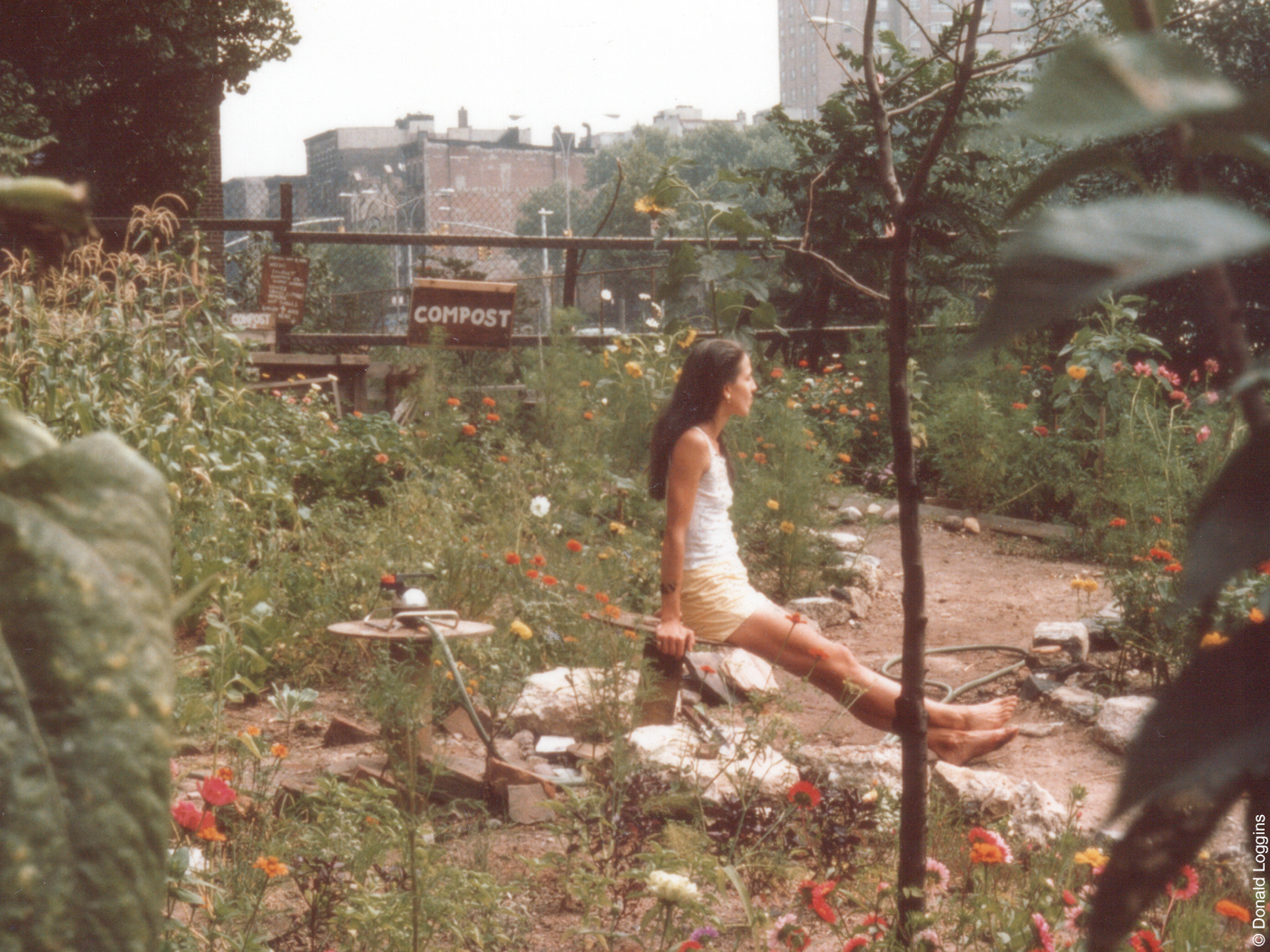Frau sitzt in einem verwilderten Garten