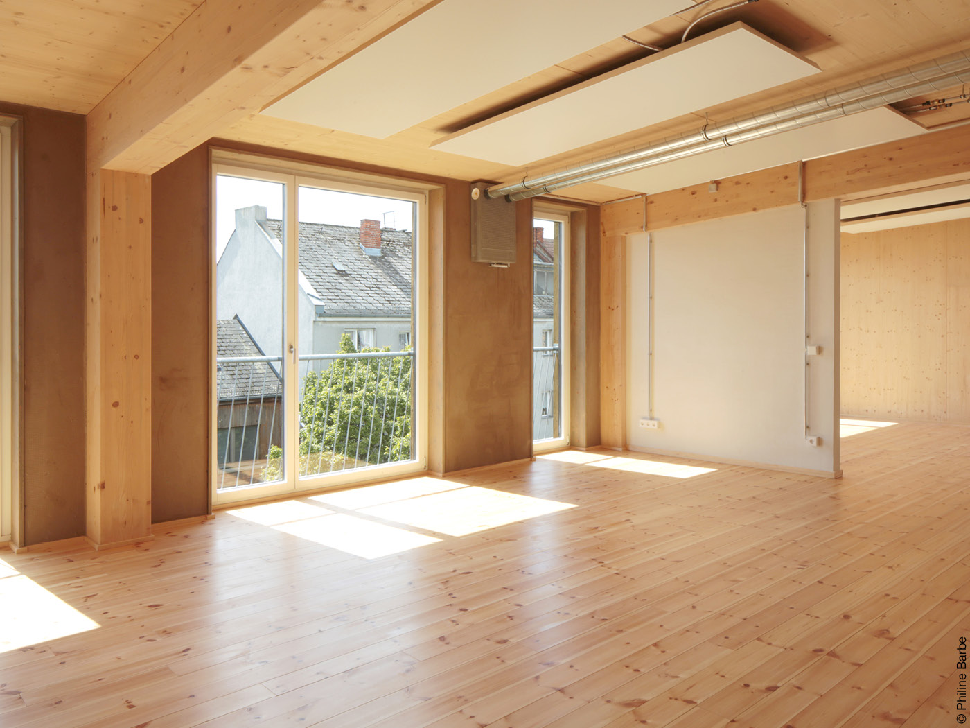 Lichtdurchfluteter Raum mit bodentiefen Fenstern und Holzvertäfelung.