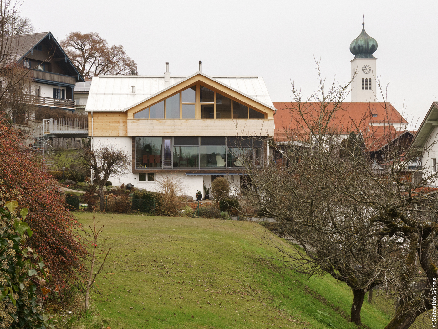 Haus mit hölzernem Obergeschoss vor Kirchturm