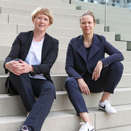 Barbara Eitner und Birte Riepenhausen von null2elf sitzen auf einer Treppe