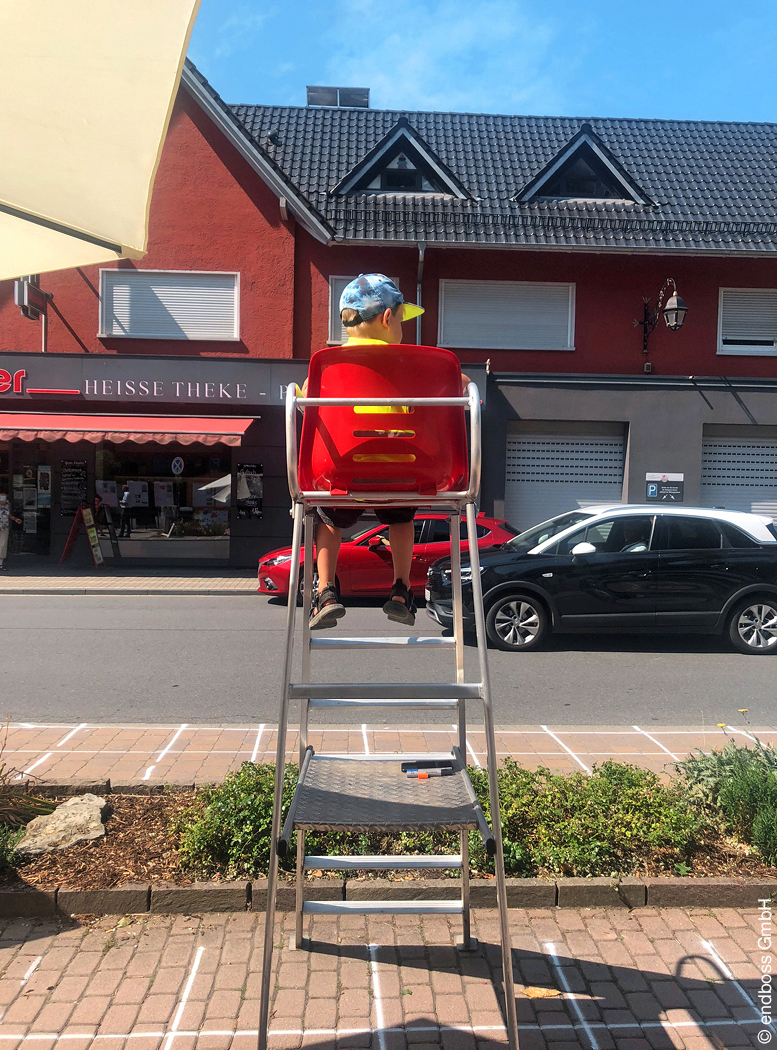 Kind sitzt am Straßenrand auf einem Hochsitz