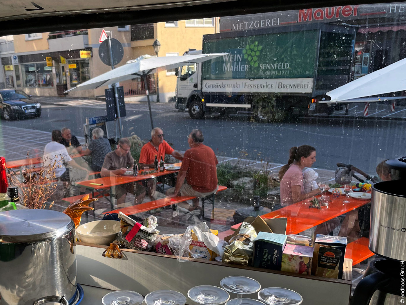 Personen bei Bürgerbeteiligung sitzen an Bierbänken an Straße und essen