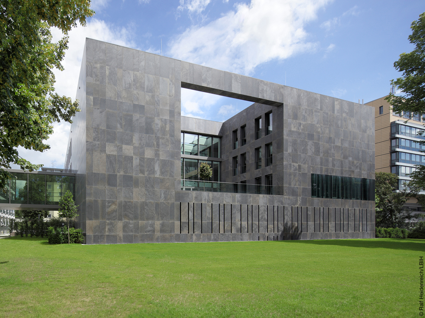 Bürohaus mit dunkler Natursteinfassade auf Wiese