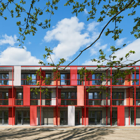 Rotes Gebäude mit vielen Fenstern, Balkonen und Sonnenschutzelementen