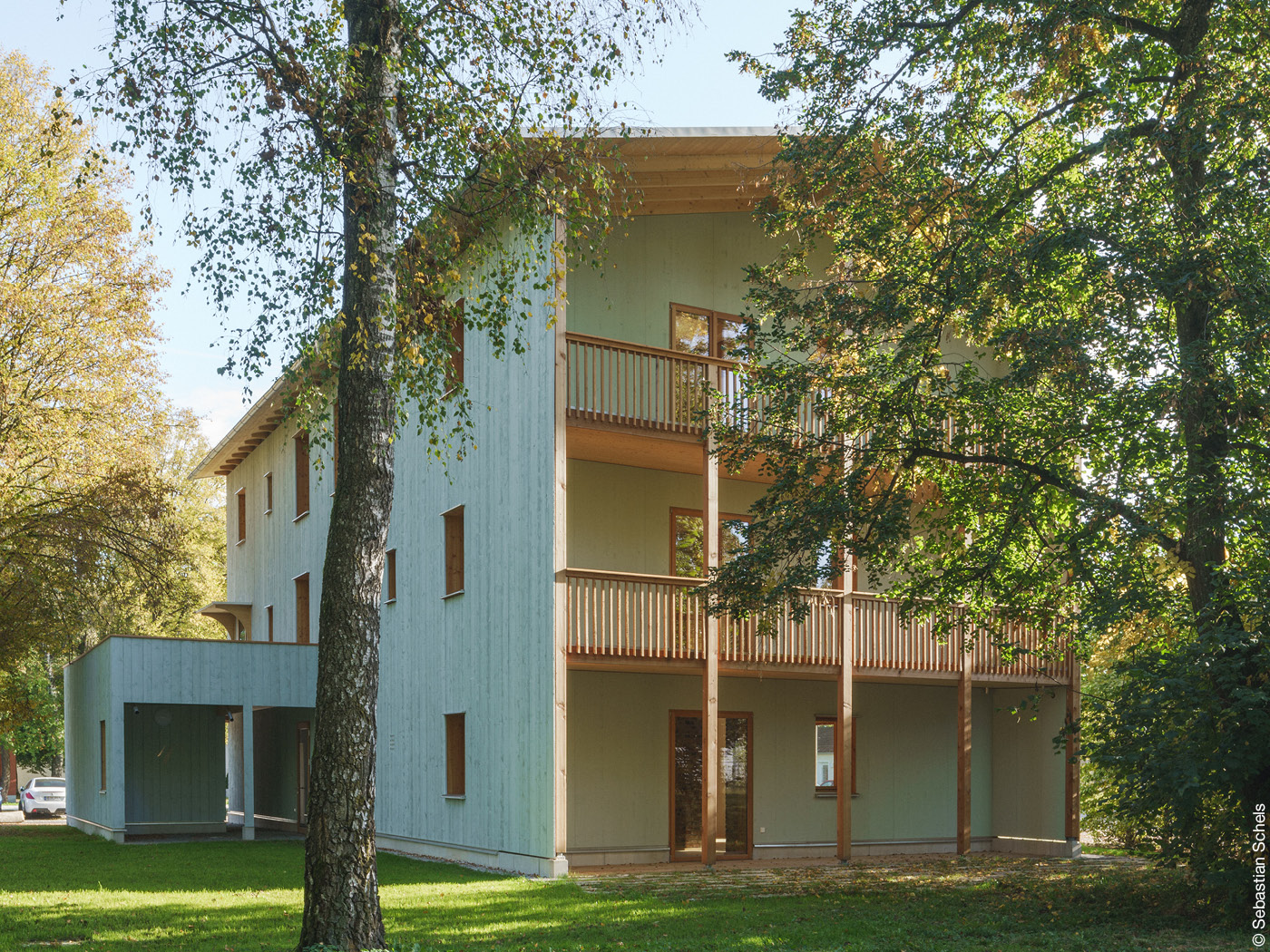 Dreistöckiges Holzhaus mit Balkonen zwischen Bäumen
