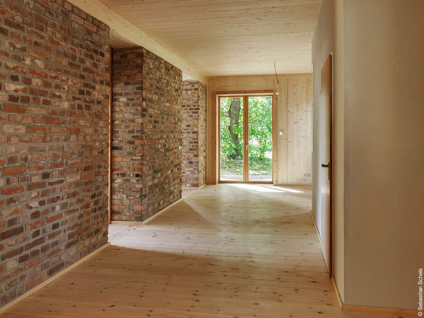 Wohnraum mit Wänden aus Ziegeln und Holzfußboden und Holzdecke