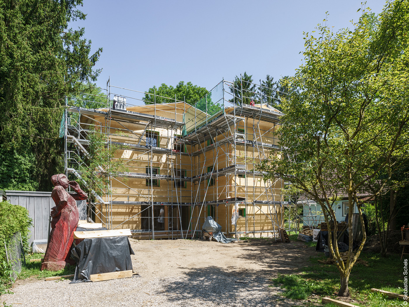 Dreistöckiges Holzhaus mit Baugerüst zwischen Bäumen