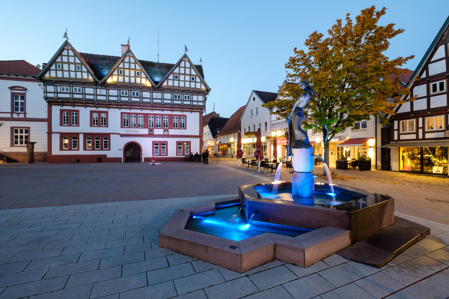 Fachwerkhaus mit Platz und blau beleuchtetem Brunnen