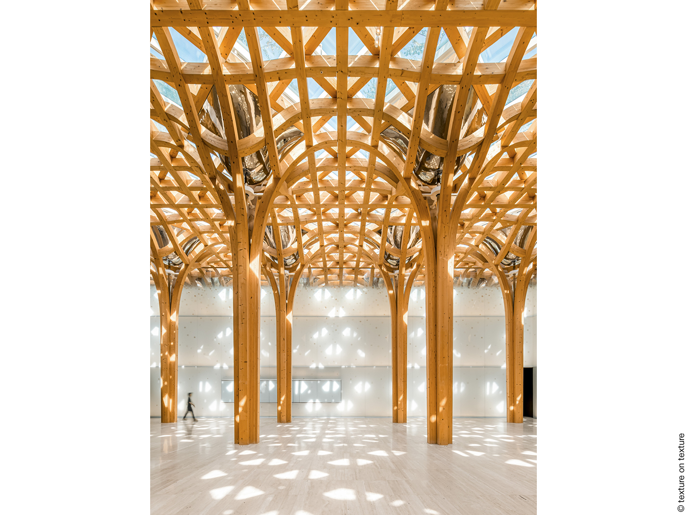 Das gläserne Dach wird von einer Holzkonstruktion getragen, die sich wier ein Wald aus Säulen unter der Decke verzweigt