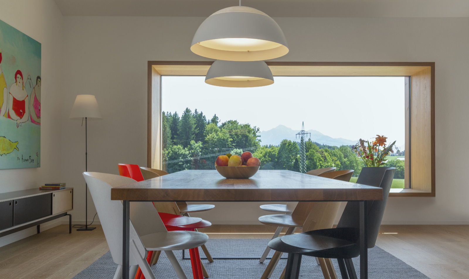 Esstisch vor großem Fenster mit Blick auf Bäume