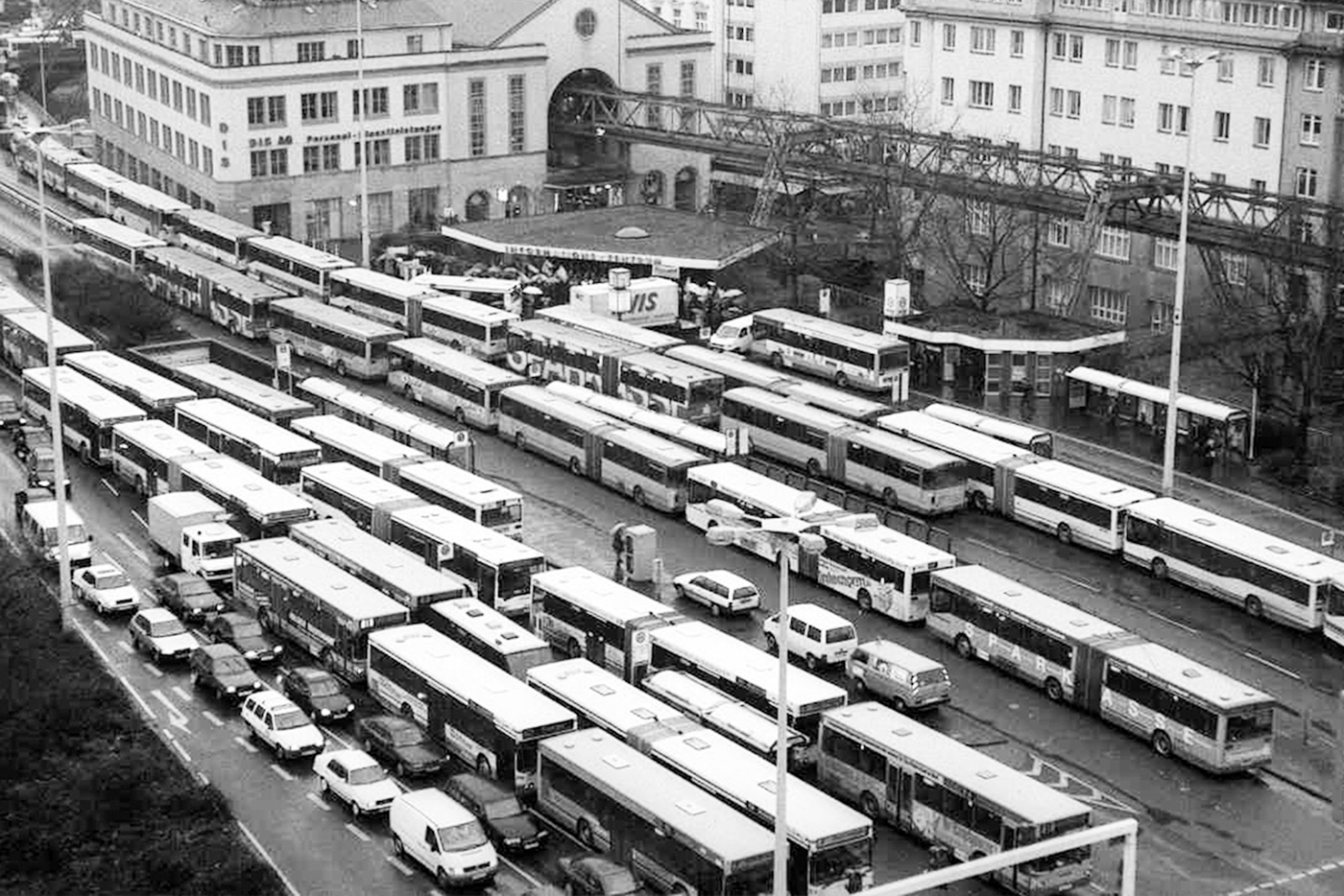 Busbahnhof Wuppertal mit vielen Bussen und Autos, dahinter Häuser