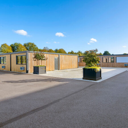 Blockhütten aus Holz, davor große Blumenkübel