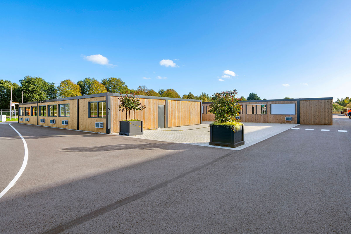 Blockhütten aus Holz, davor große Blumenkübel