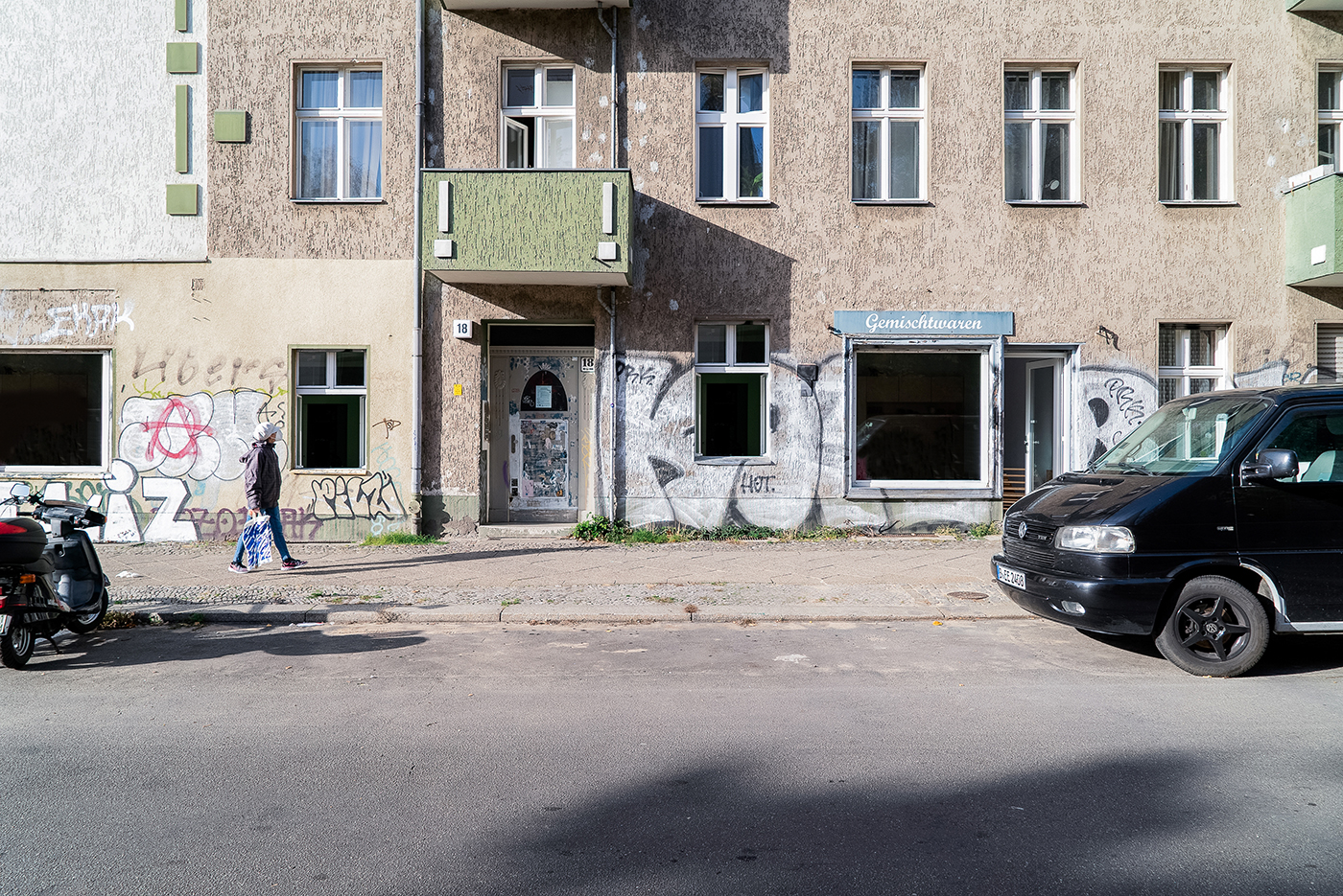 Braune Hausfassade mit mintgrünen Balkonen und Graffiti