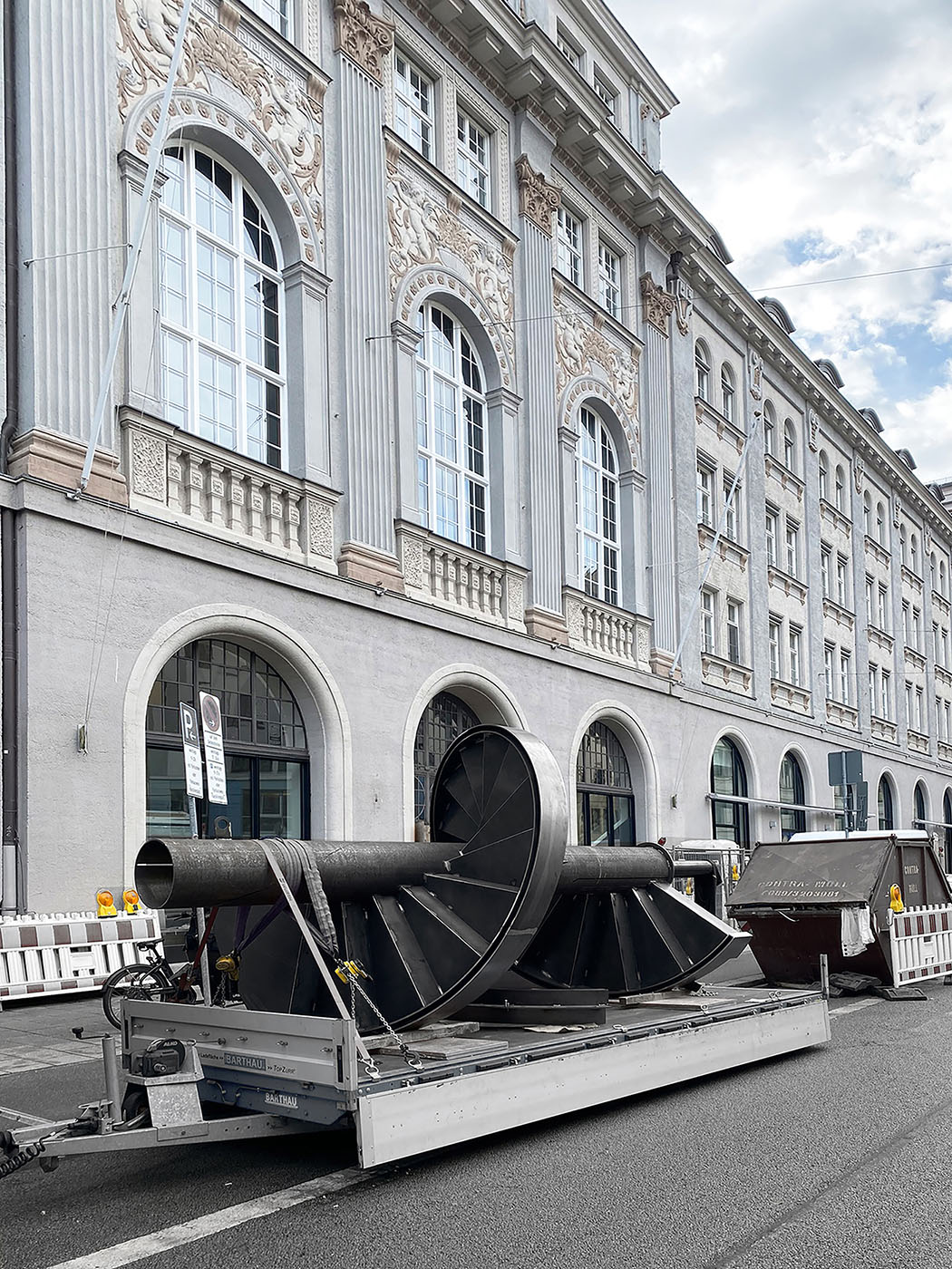 Mit Stuck verzierte Hausfassade im Jugendstil, davor eine liegende Spindeltreppe aus Stahl.