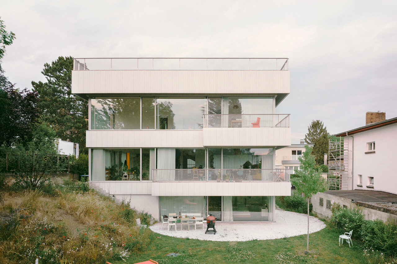 Quadratisches Haus mit breiten Fensterfronten, Balkonen und einer kreisförmigen Terrasse und Garten im Erdgeschoss