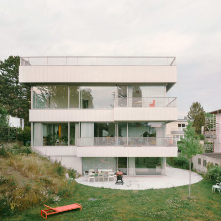 Quadratisches Haus mit breiten Fensterfronten, Balkonen und einer kreisförmigen Terrasse und Garten im Erdgeschoss