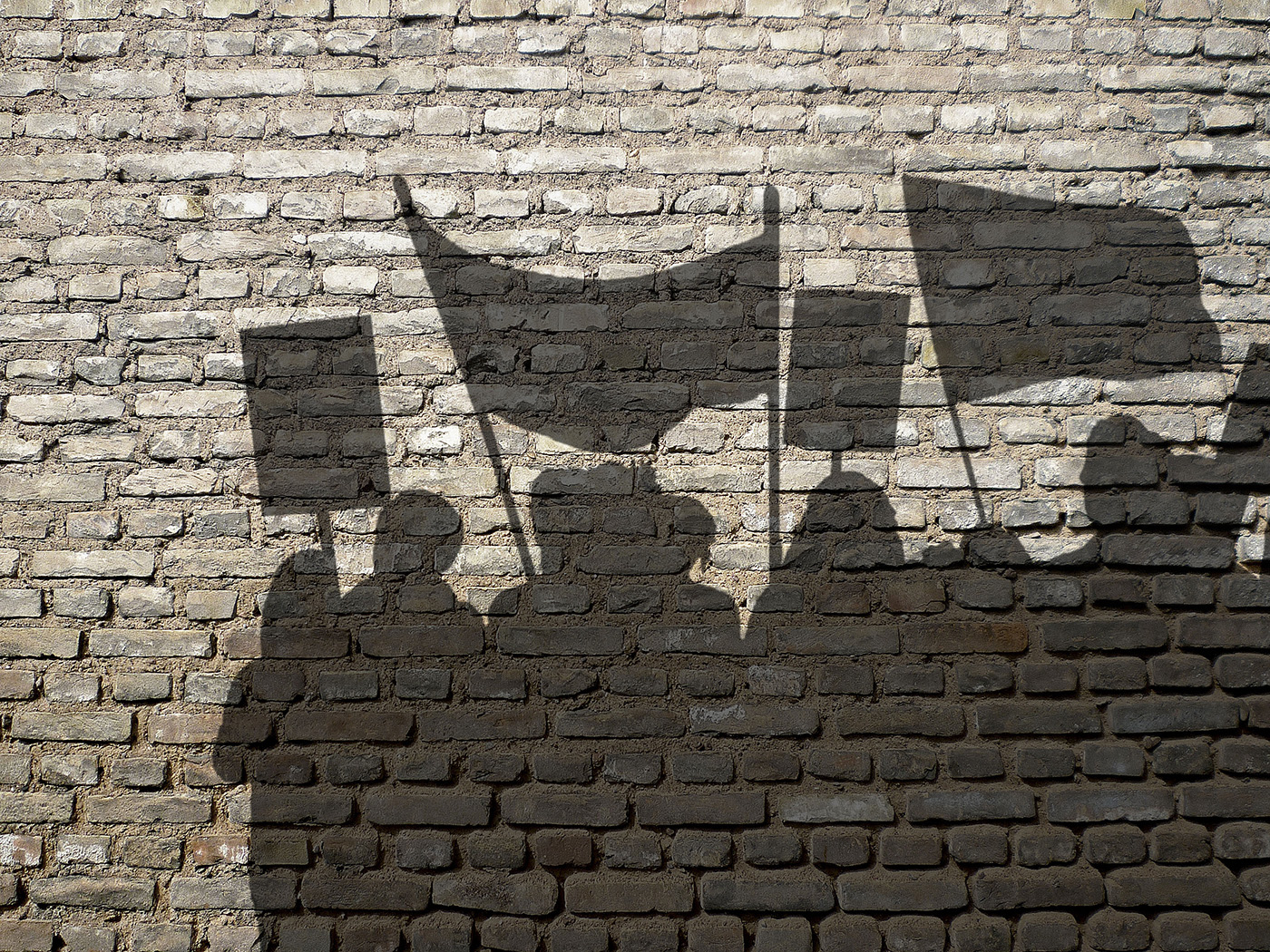 Die Schatten streikender Personen auf einer Backsteinmauer 