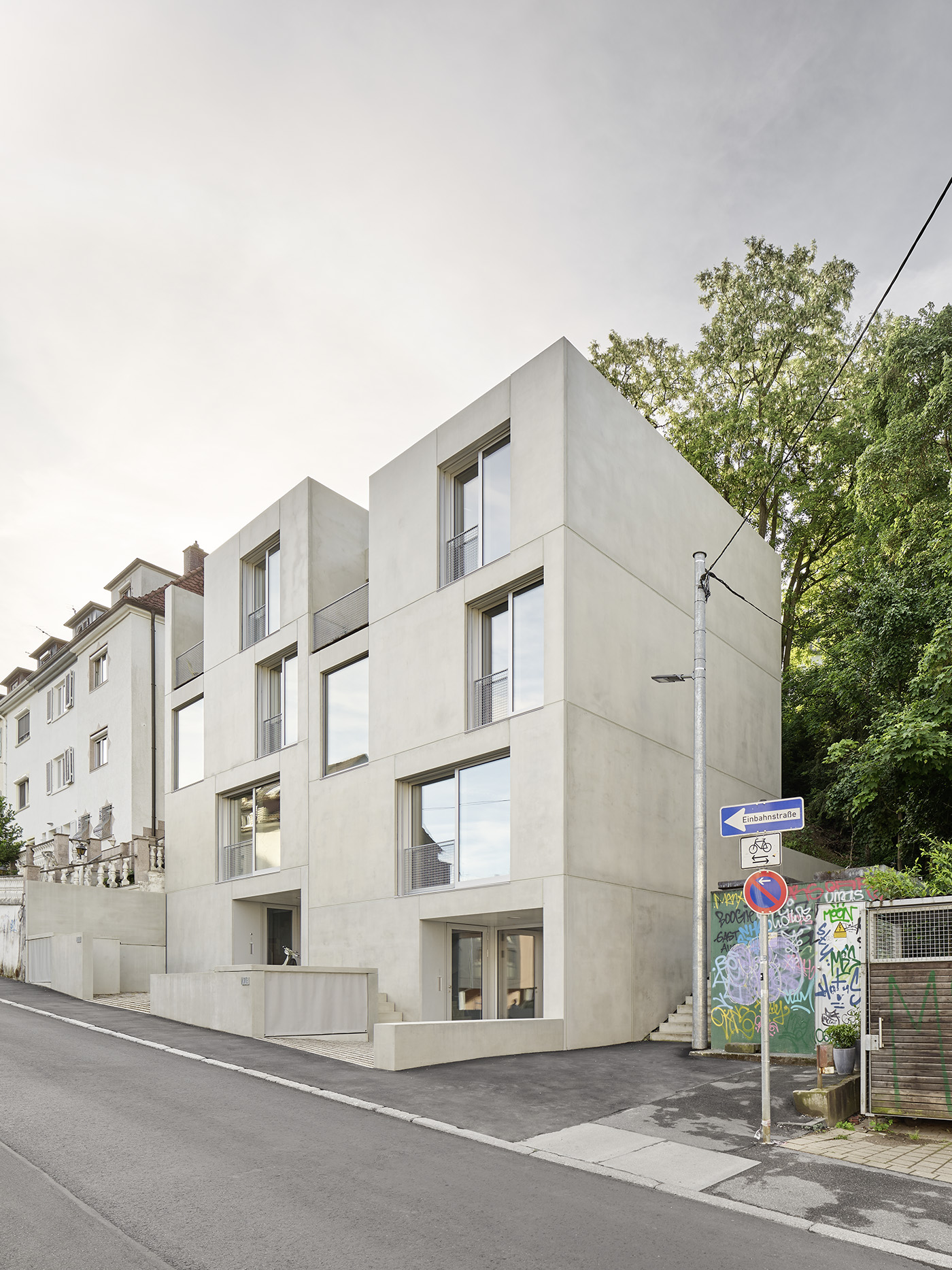 Rechteckiges Doppelhaus mit grau-beiger Fassade und vielen großen Fenstern.