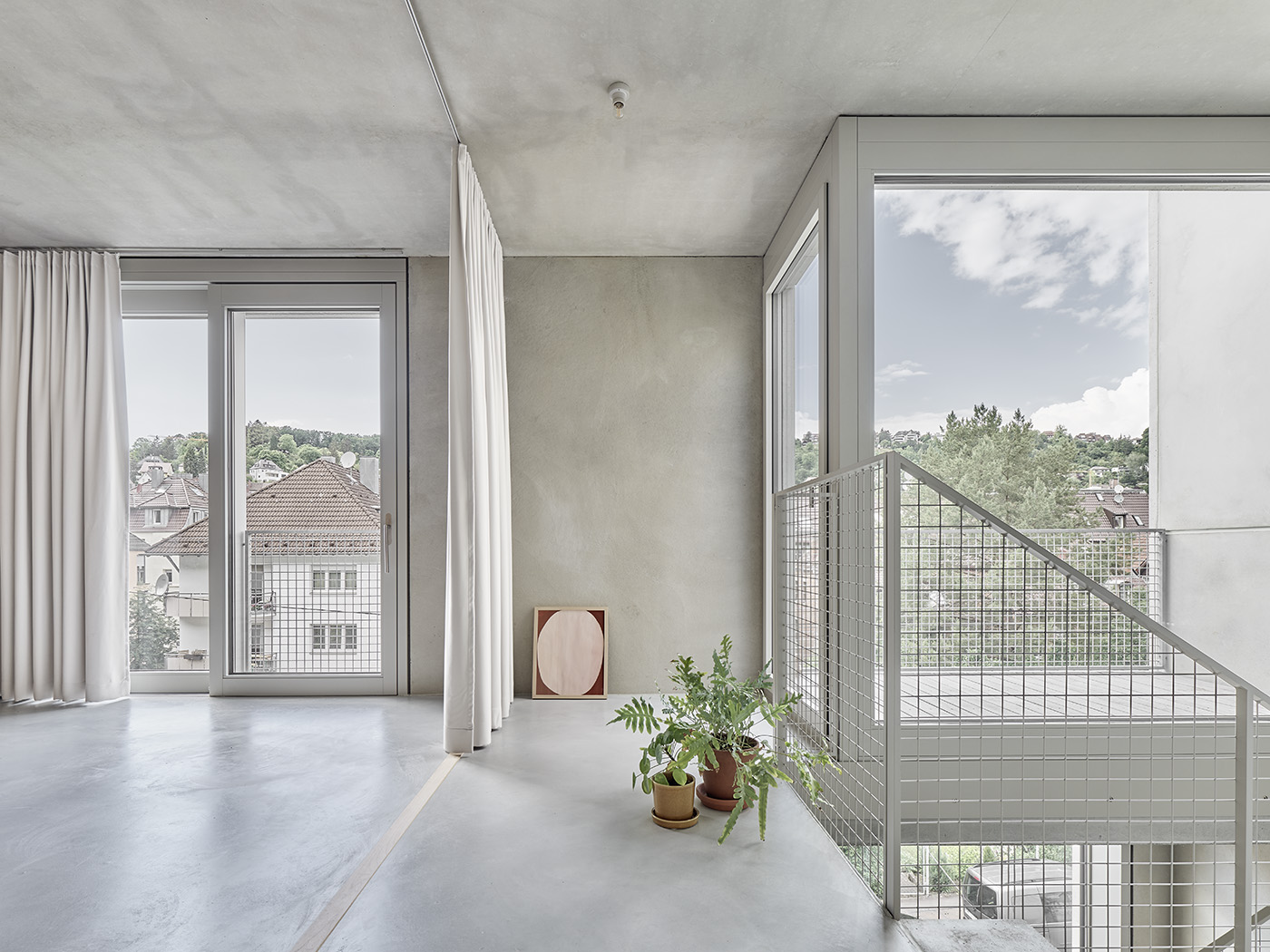 Helle Wohnung mit Estrichboden, viel Beton, Vorhängen als Raumtrennern und Treppe