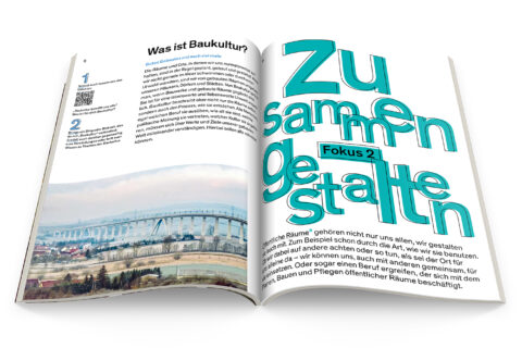 Aufgeschlagenes Schulbuch der Bundesstiftung Baukultur, zu sehen ist ein Text mit einer mintgrünen Überschrift und einem Foto von einer Brücke, die über Felder führt.