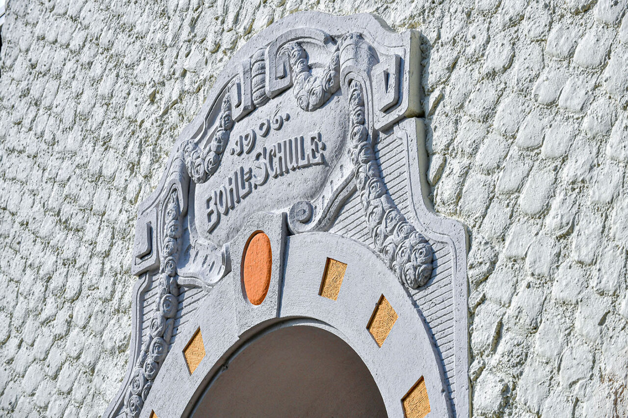 Fassade der Bohlschule in Aalen mit verziertem Stuck und grobem Putz in grau-beige