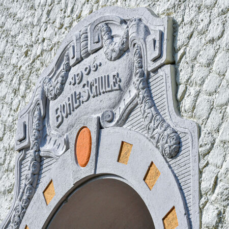 Fassade der Bohlschule in Aalen mit verziertem Stuck und grobem Putz in grau-beige