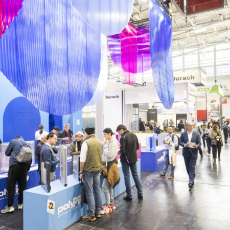 Messestand auf der Messe Bau mit violetten Möbeln und von der Decke hängenden Kreisen