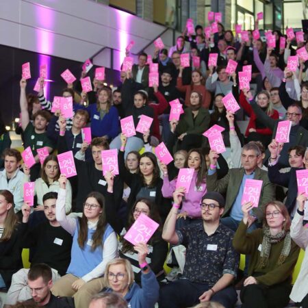 Publikum auf dem Nachwuchsarchitektentag bei Abstimmung mit rosa Karten