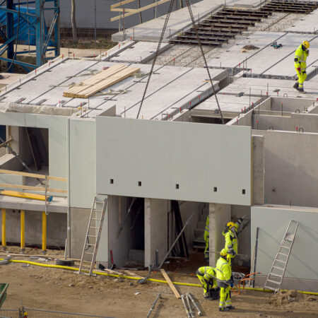 Baustelle mit einer Fassadenplatte aus Beton an einem Kran