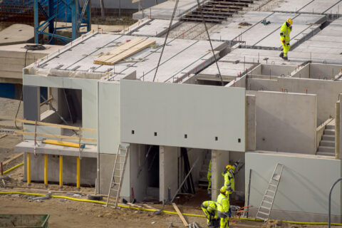 Baustelle mit einer Fassadenplatte aus Beton an einem Kran