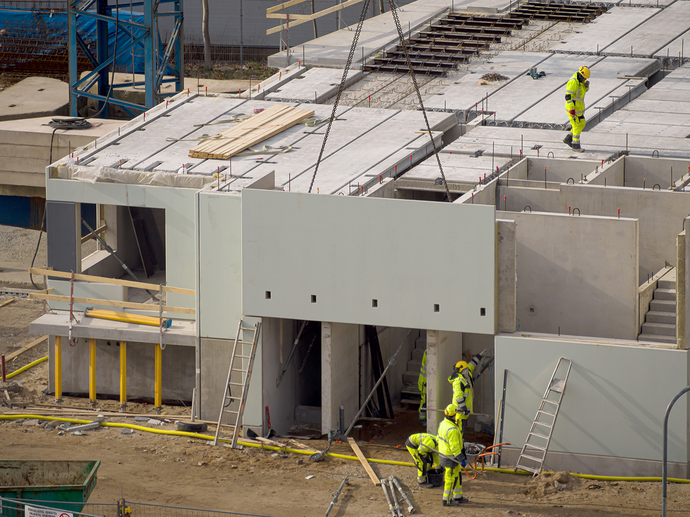 Baustelle mit einer Fassadenplatte aus Beton an einem Kran