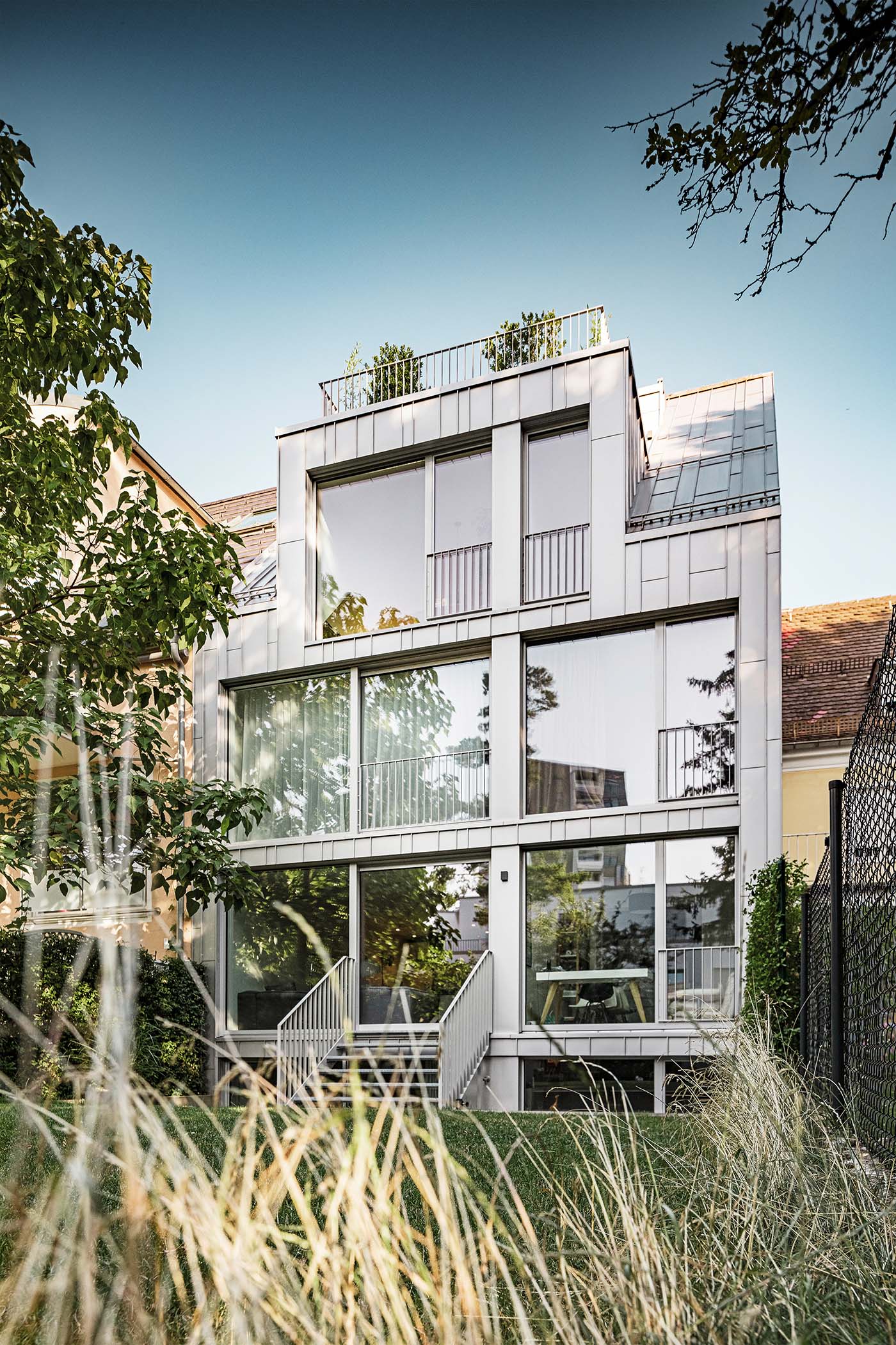 Hausfassade zu einem Garten hin mit vielen großen Fenstern