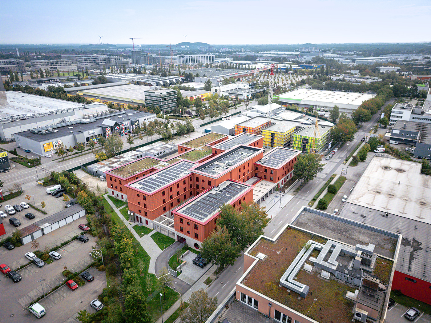 Luftaufnahme Obdachlosenhaus mit roter Fassade und Solarzellen auf dem Dach