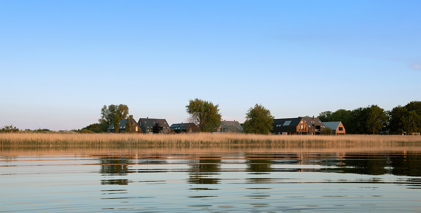 Häuser auf Rügen mit Wasser und Schilf im Vordergrund